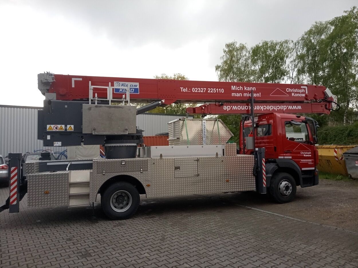 Ein roter Autokran der auf einem Parkplatz steht.