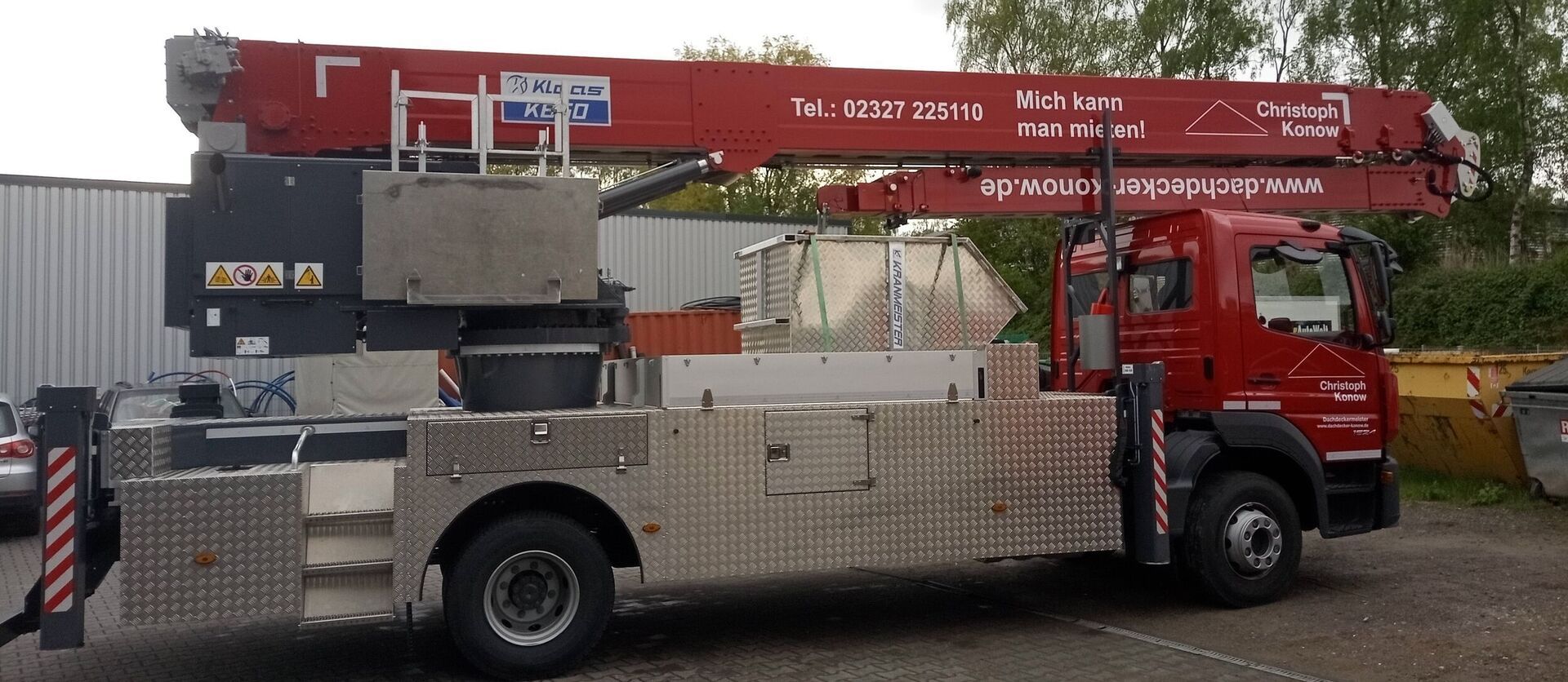 Ein roter Autokran der auf einem Parkplatz steht.